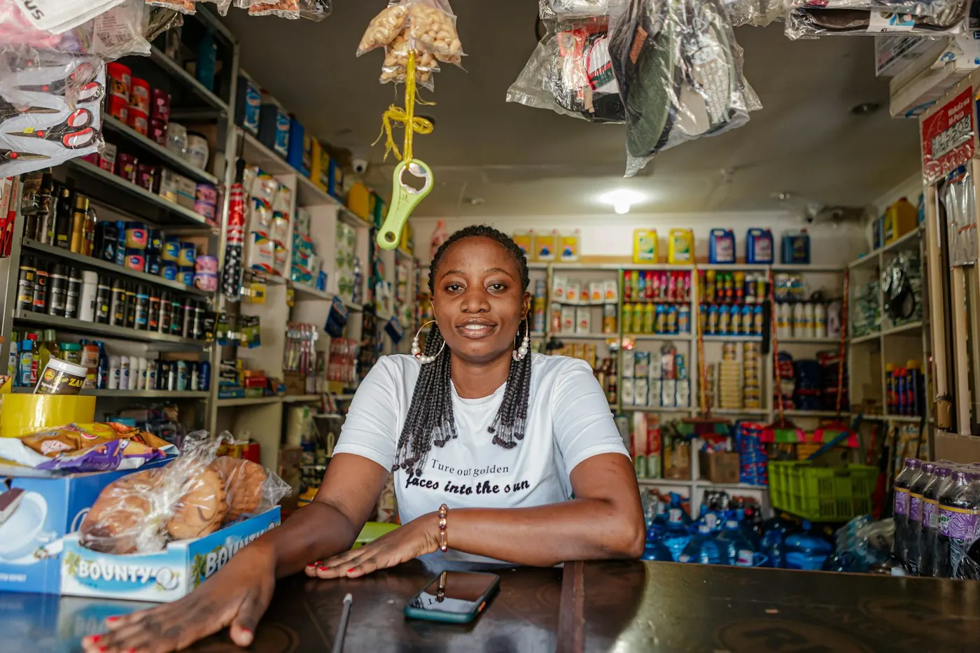 A shop owner smiling behind the counter of her duka